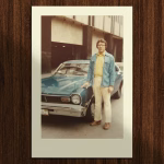 DaleCar » Tree9 Films Polaroid-style photo of a man in a denim jacket and yellow shirt standing beside a blue vintage car on a city street, 1970s vibe.